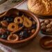 Ошав от сушени сливи, ябълки, круши и смокини в глинена купа до питка, орехи и мед на трапезата за Бъдни вечер